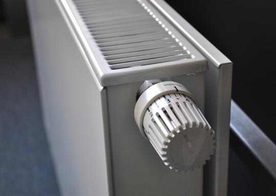 image shows side view of white radiator with valve facing camera.