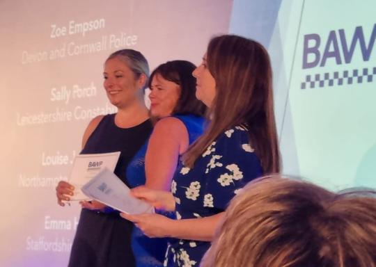 Image of 3 women standing up on stage receiving an award