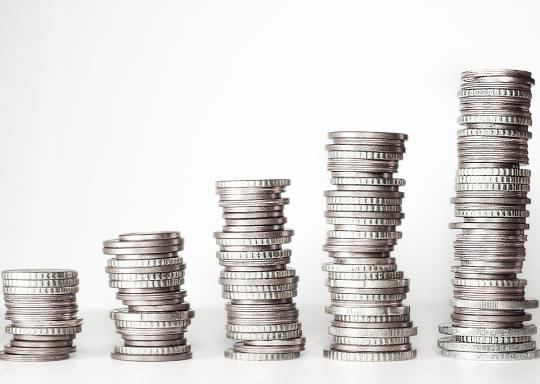 image shows five columns of silver coins on a white background ascending in height