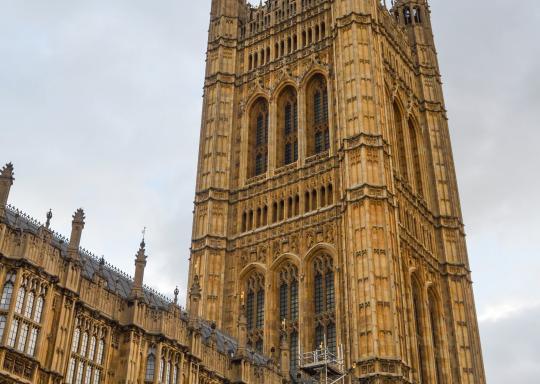 Photo of the palace of westminsiter taken from the side which faces onto Parliament Square. A union flag is flying from the flagpole at top of the palace.