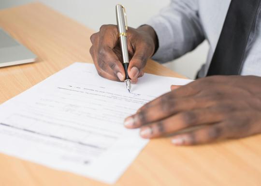 Image of a man signing a piece of paper