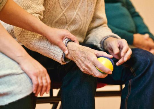 Image of a younger carer holding the hand of an older person
