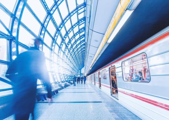 Image shows an underground station. A train is arriving at a level platform.