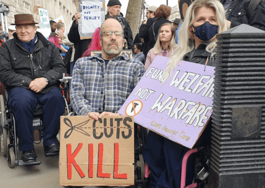 Disabled protestors holding a placard that says cuts kill