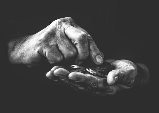Image is black and white. A pair of hands count some pennies.