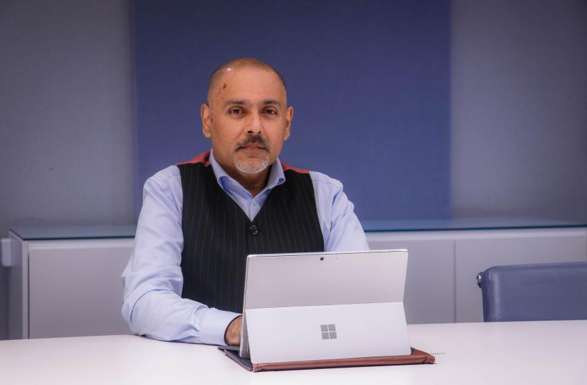 Kamran Mallick, Disability Rights UK sits in front of a laptop